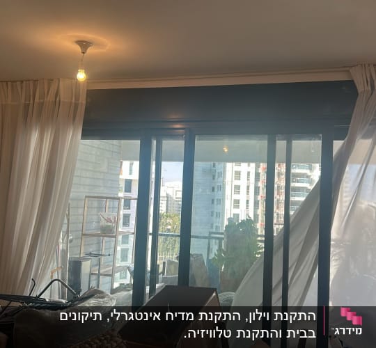 וילונות תלויים על חלון זכוכית גדול עם נוף עירוני